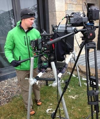 Camera operator using a camera slider and support rig on location during a professional production